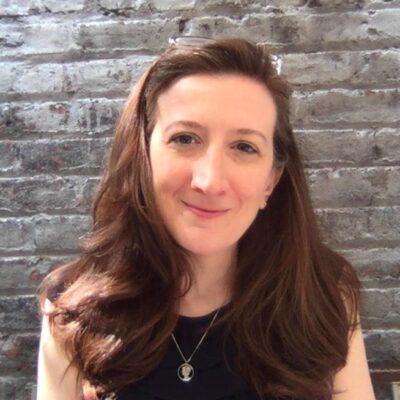 Portrait of Michelle Miller smiling against a brick wall background.