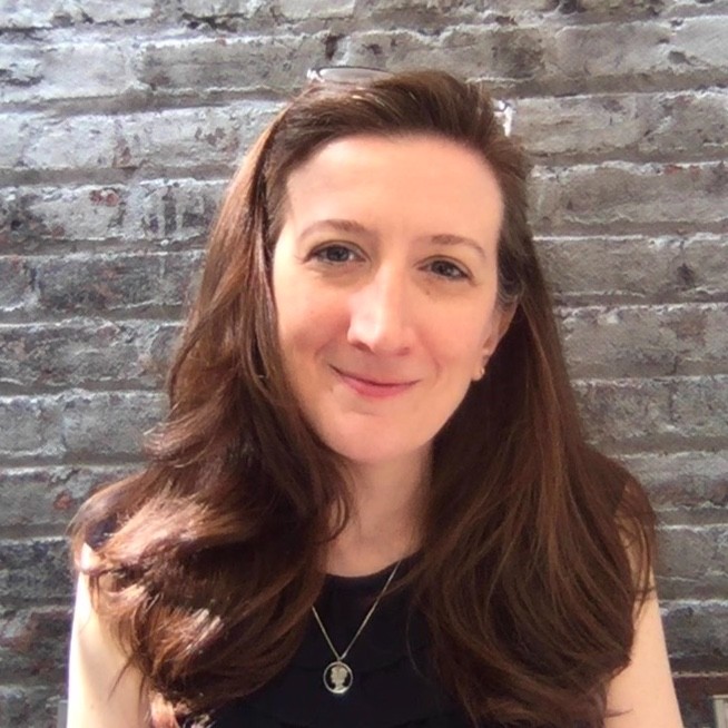 Portrait of Michelle Miller smiling against a brick wall background.