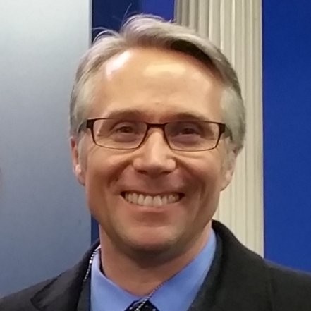 Portrait of Mark DeLoura smiling with glasses.